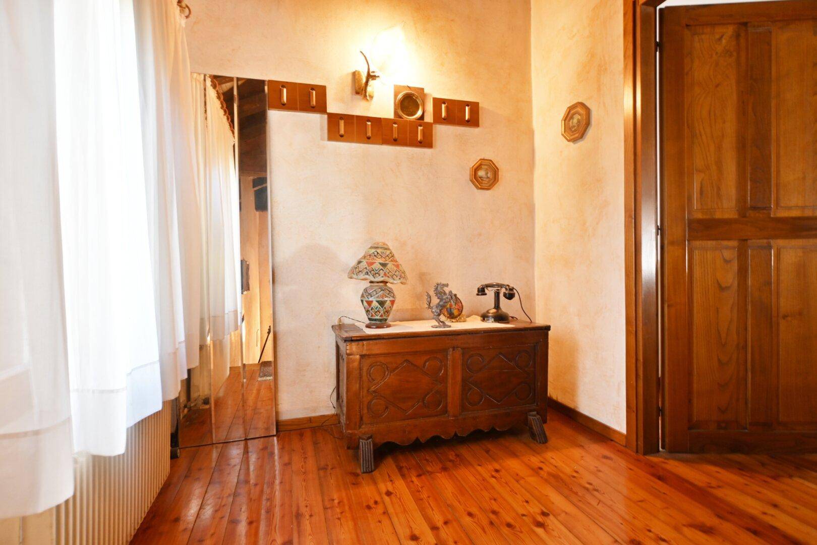 Gemütlicher Flur mit Holzboden, antiker Truhe und Garderobe an der Wand.