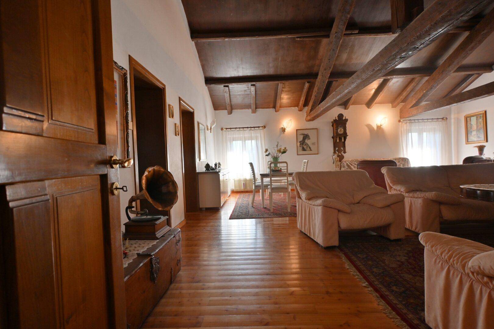 Großer Wohn- und Essbereich mit Holzboden, Holzbalkendecke und bequemen Sofas.