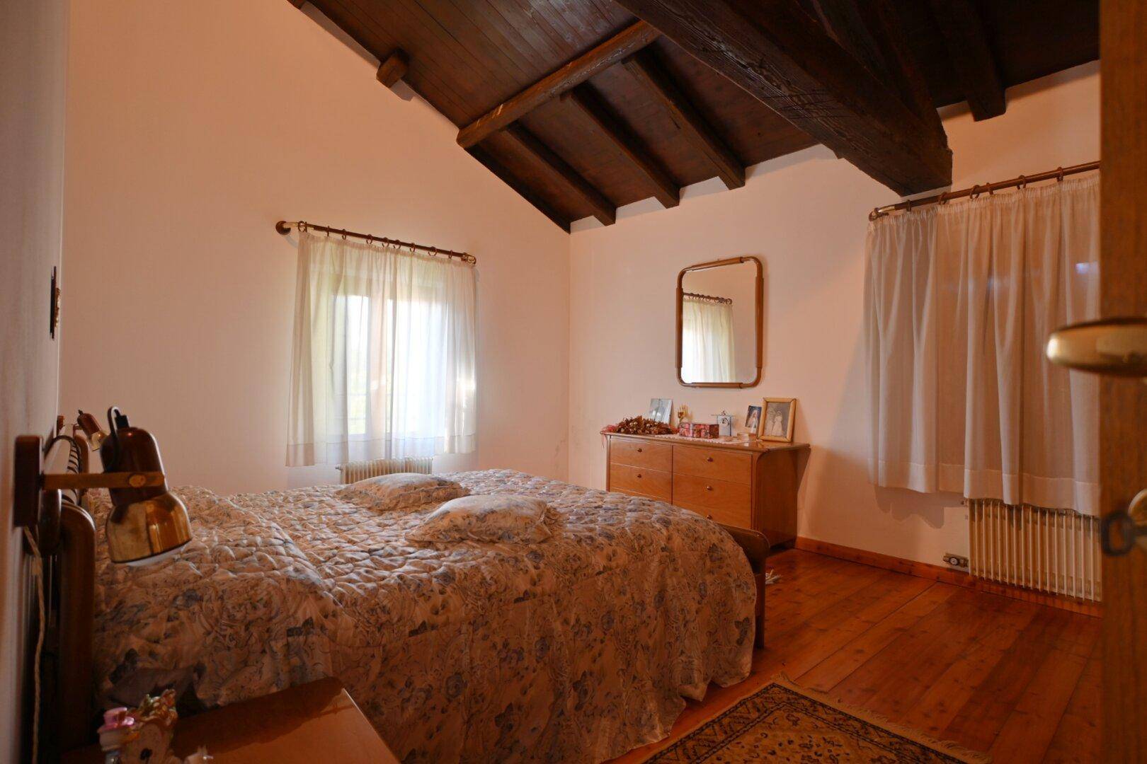 Schlafzimmer mit Holzboden, schrägen Decken und Doppelbett.