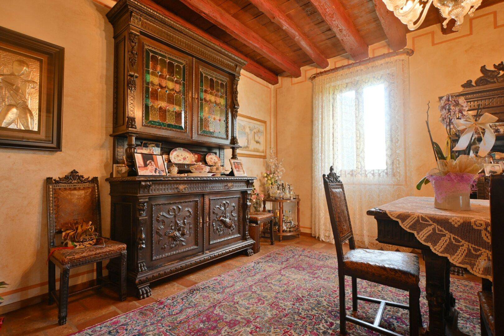 Antiker Holzschrank im Esszimmer mit Terrakottaboden und traditioneller Einrichtung.