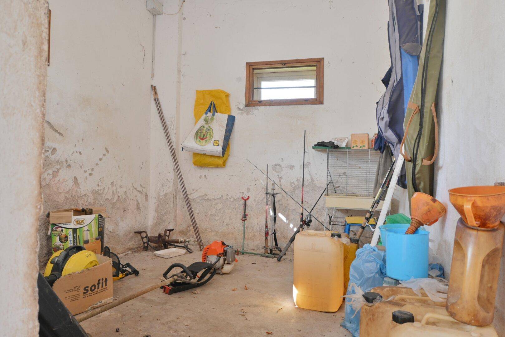 Abstellraum mit unfertigen Wänden, kleinem Fenster und verschiedenen Geräten.