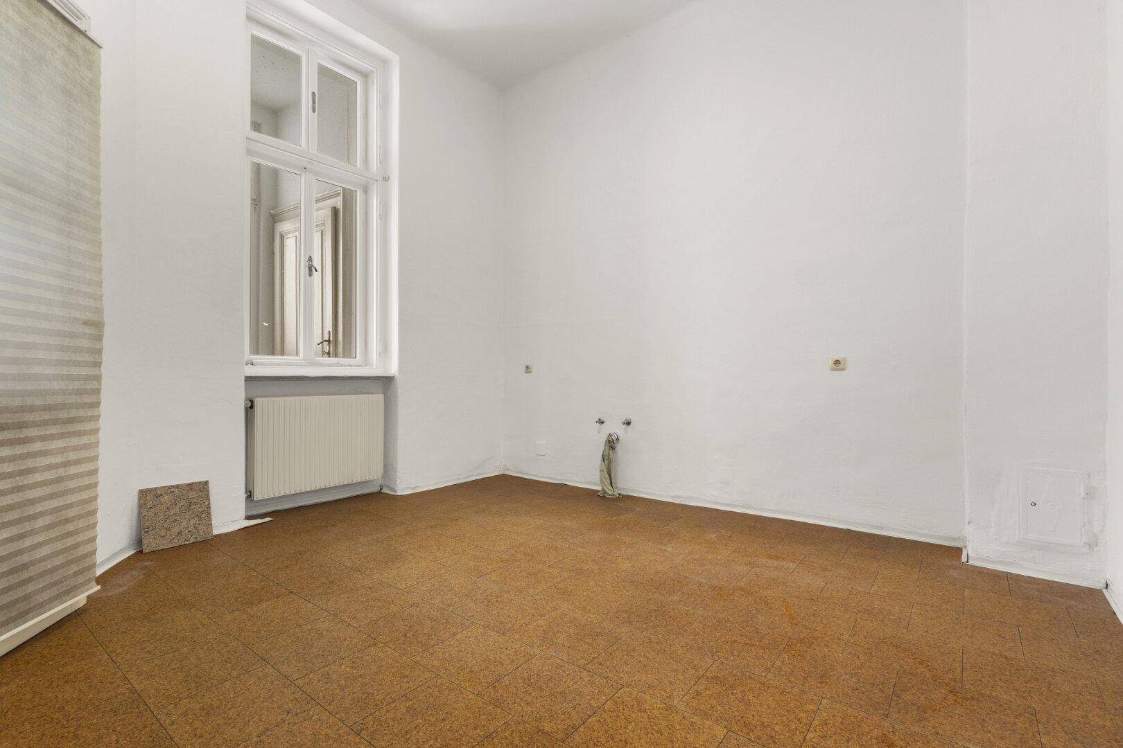 Leerer Raum mit Linoleumboden und einem Fenster, der Renovierungsbedarf aufweist.