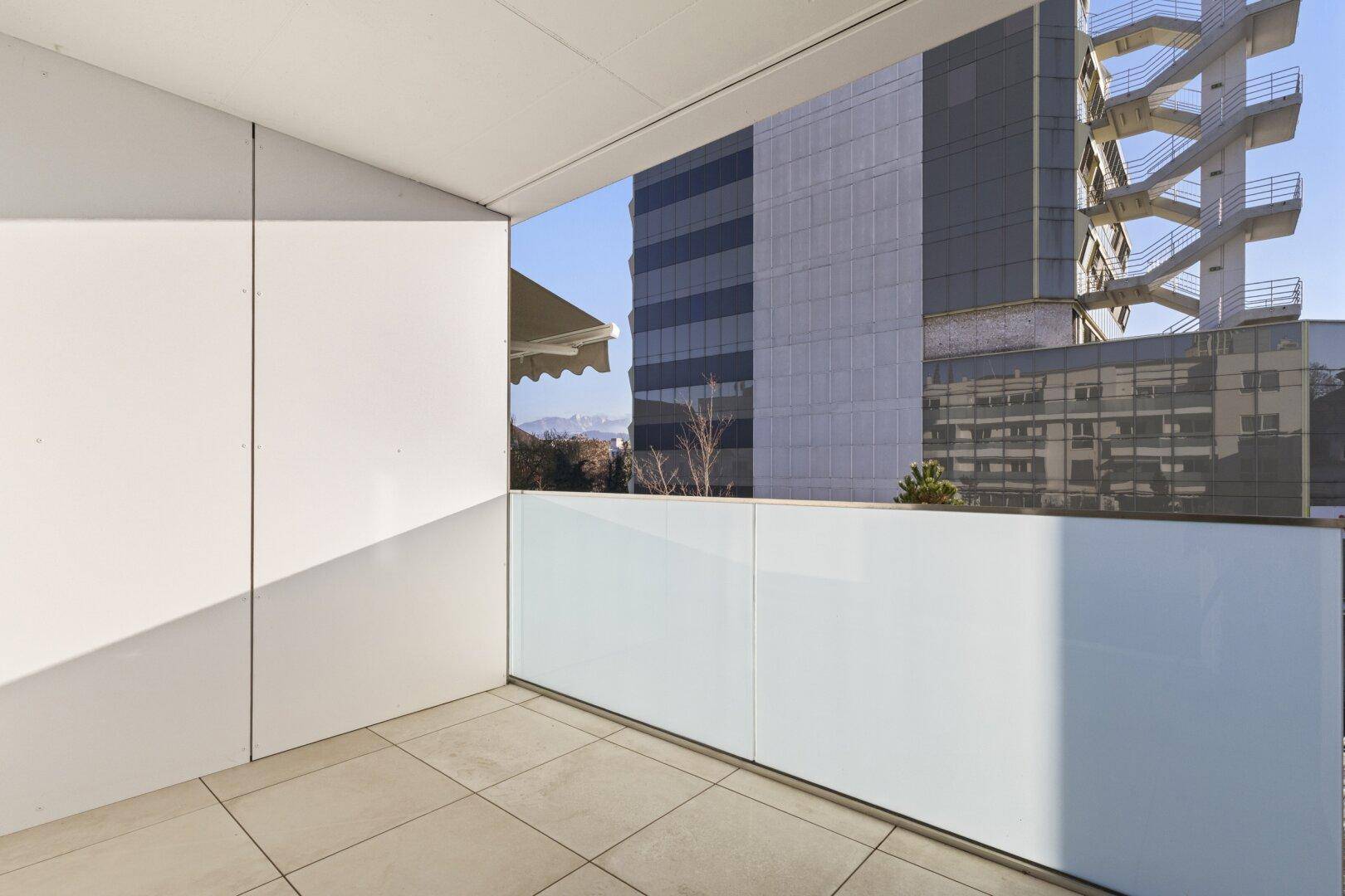 Geräumiger Balkon mit Blick auf die Stadt und die umliegenden Gebäude unter blauem Himmel.
