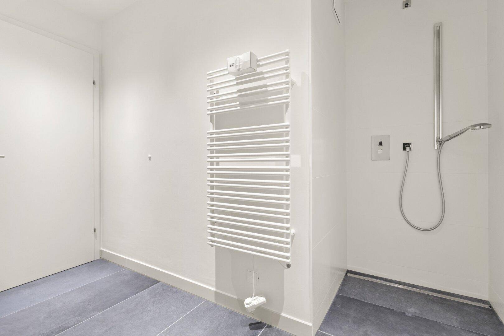 Modernes Badezimmer mit ebenerdiger Dusche und beheiztem Handtuchhalter.