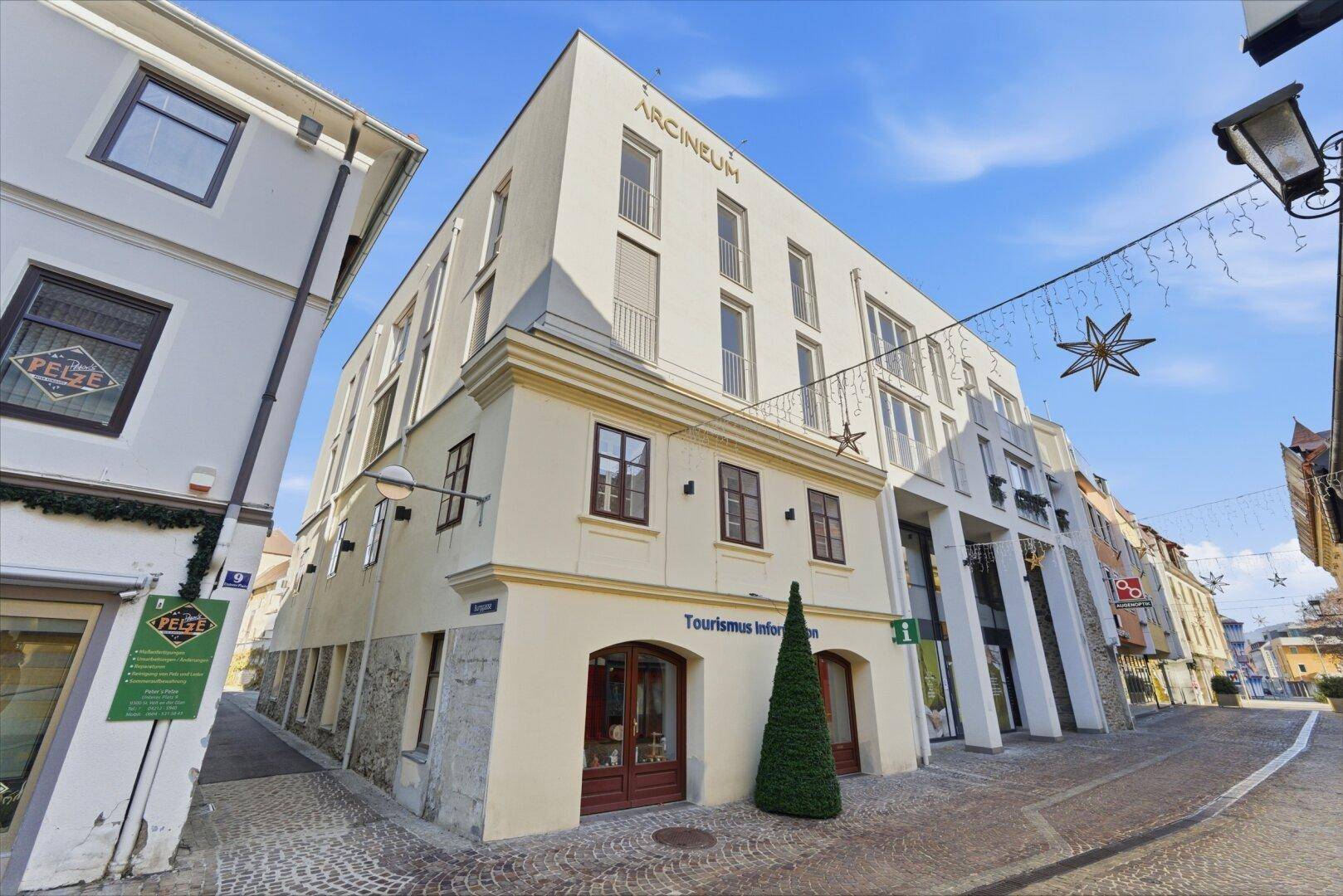 Ansicht eines modernen Gebäudes mit Geschäften im Erdgeschoss in einer belebten Stadtstraße.