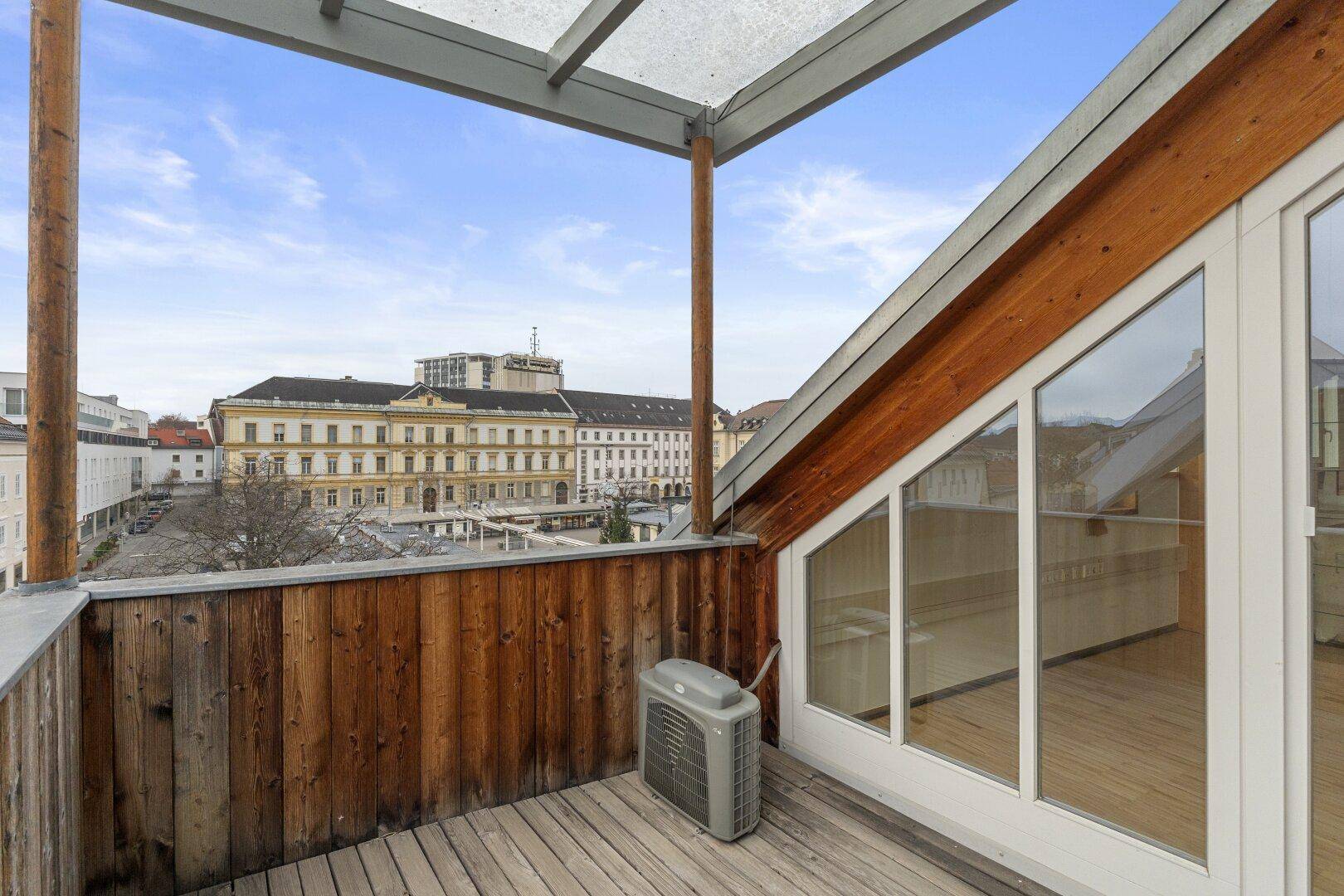 Kleiner Balkon mit Holzboden und Blick auf die Stadt, bietet einen geschützten Außenbereich.