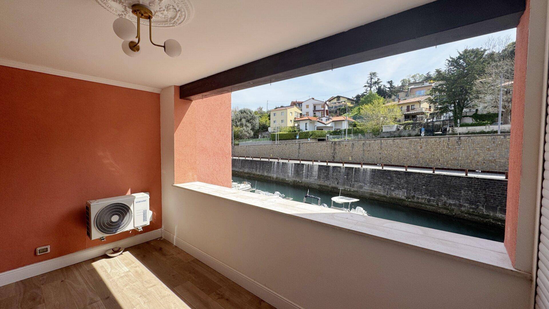 Leerer Raum mit großem Fenster und Klimaanlage, bietet einen hellen Blick auf den Kanal.