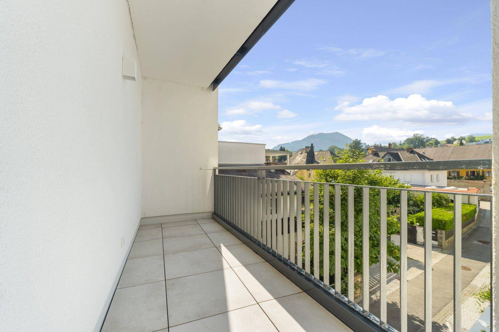 Geräumiger Balkon mit Fliesenboden und modernem Geländer, bietet einen weiten Blick.
