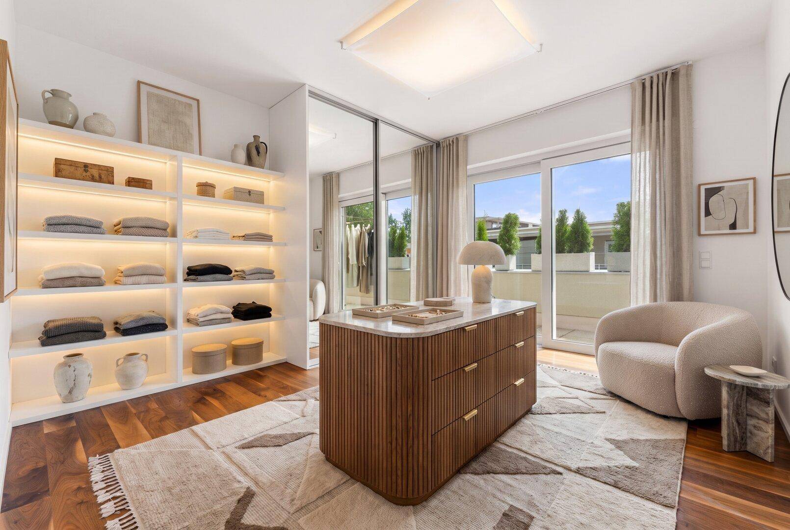 Elegantes Ankleidezimmer mit beleuchteten Regalen, Mittelinsel und Terrassenzugang.