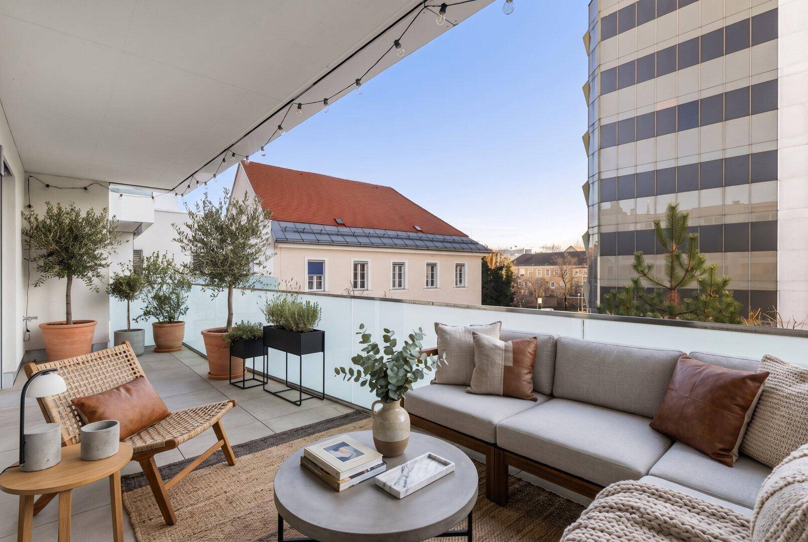 Großer Balkon mit Sitzgelegenheiten, Pflanzen und Stadtblick.