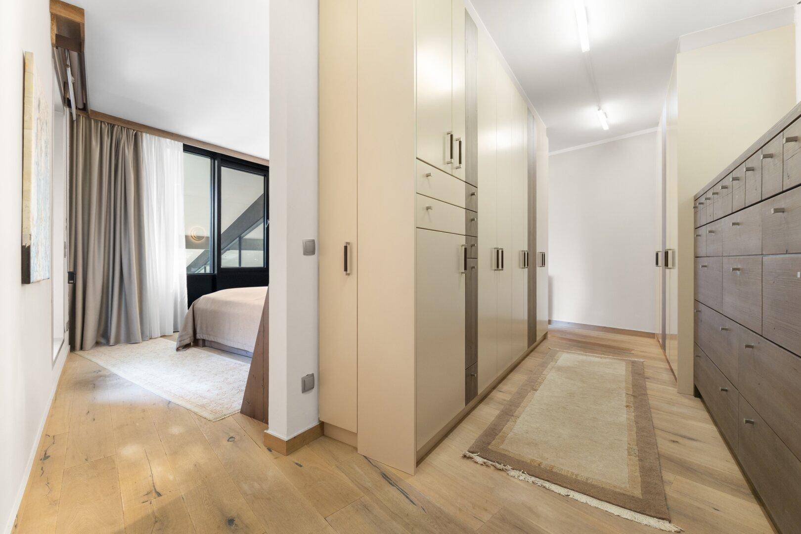 Geräumiger begehbarer Kleiderschrank mit vielen Einbauschränken und Holzboden.