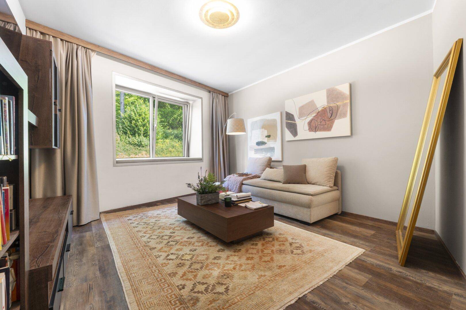 Gemütliches Wohnzimmer mit Sofa, Couchtisch und Blick ins Grüne.