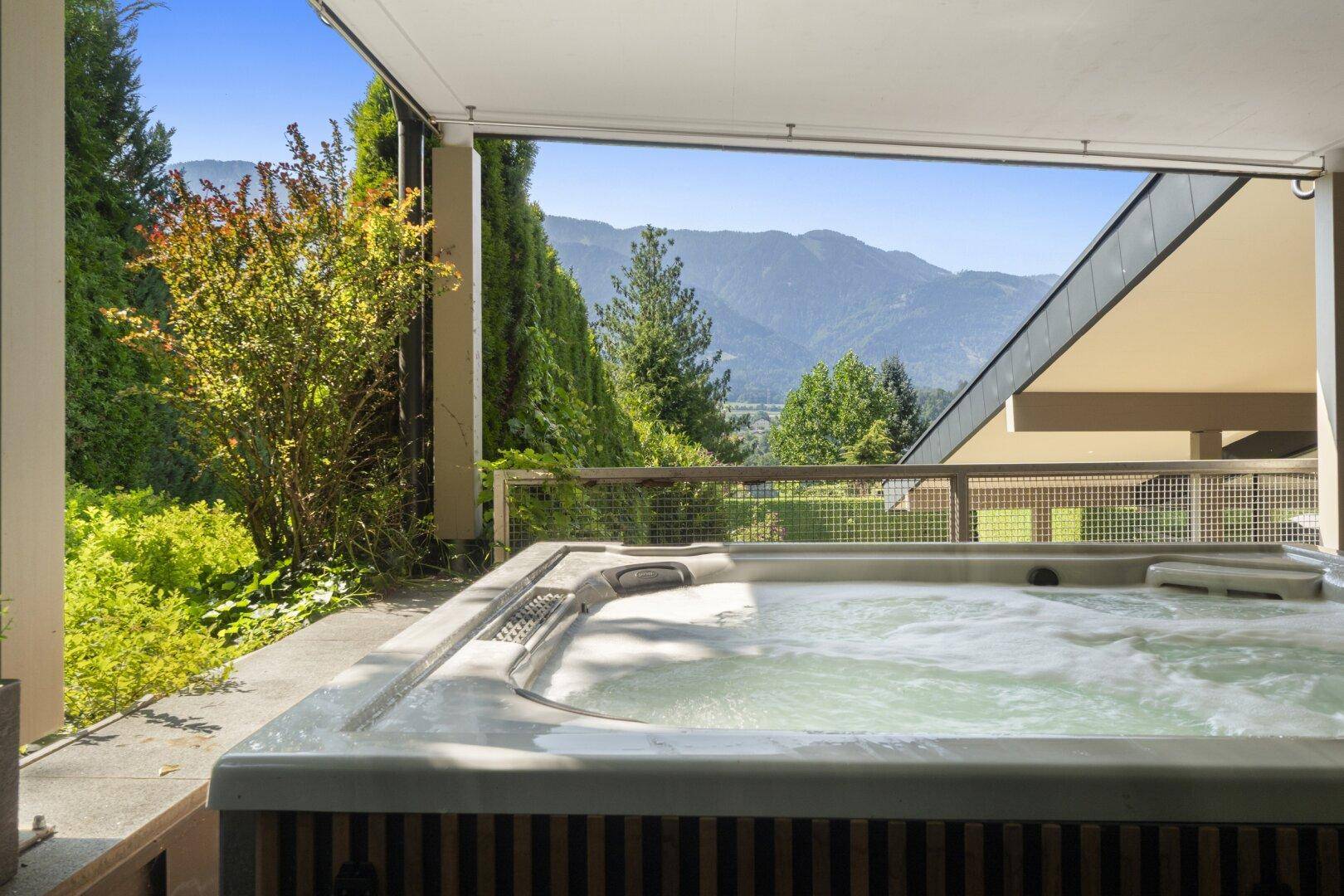Überdachte Terrasse mit Whirlpool und Panoramablick auf die Berge.