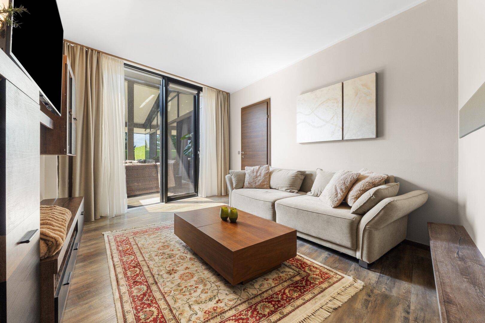 Komfortables Wohnzimmer mit Zugang zur Terrasse und modernem Interieur.