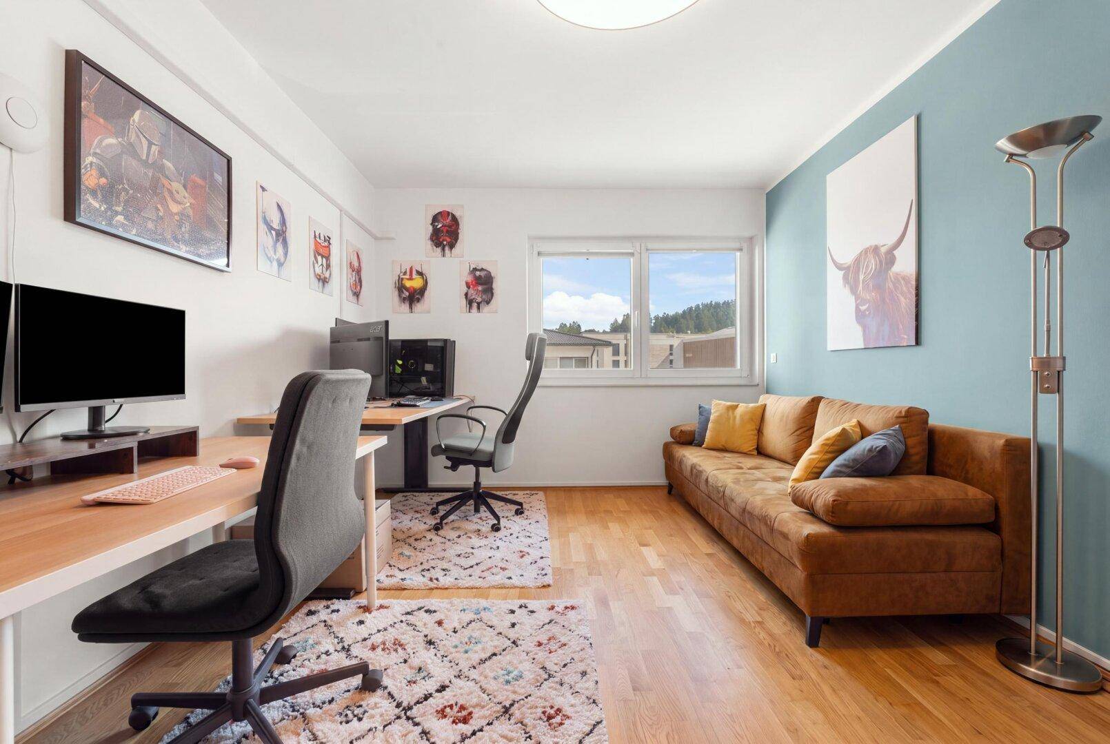 Geräumiges Arbeitszimmer mit zwei Schreibtischen, Sofa und Blick ins Grüne.