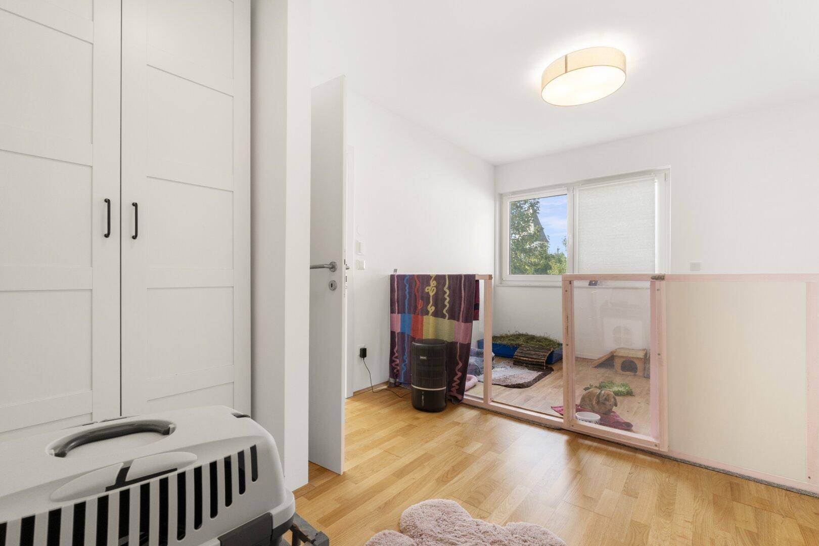 Helles Zimmer mit Einbauschrank und Holzboden, derzeit als Haustierbereich genutzt.