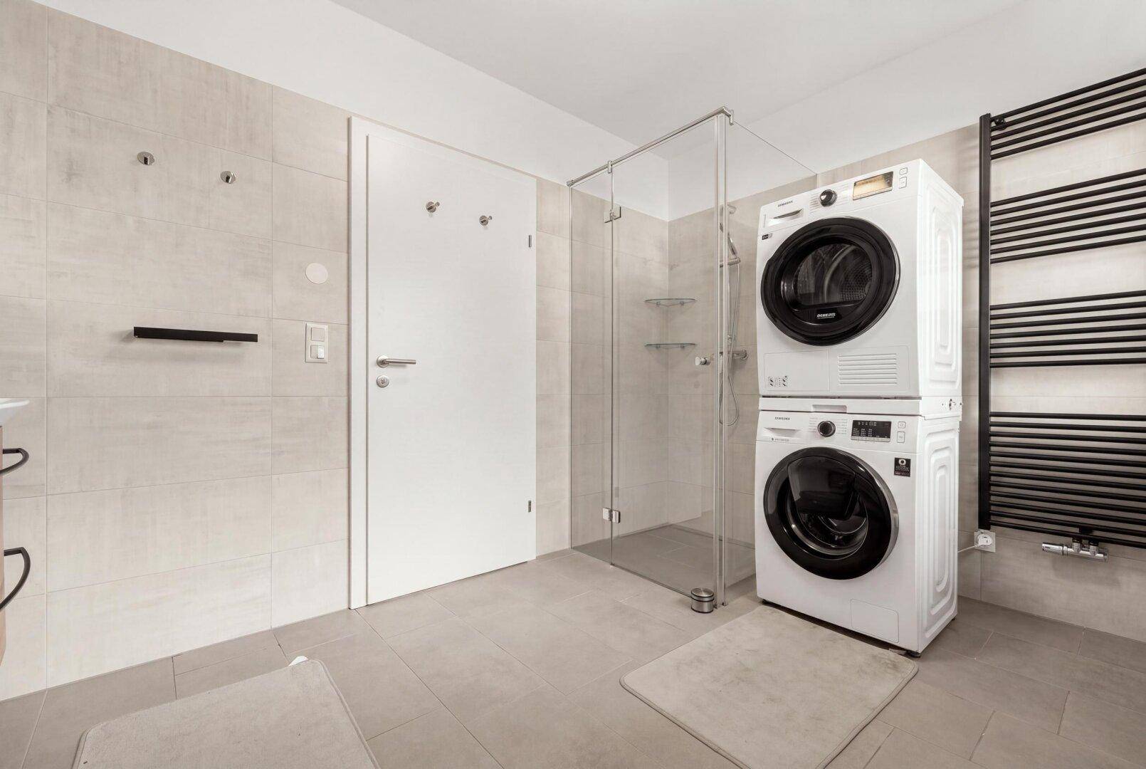 Geräumiges Badezimmer mit ebenerdiger Dusche, Waschmaschine und Trockner.
