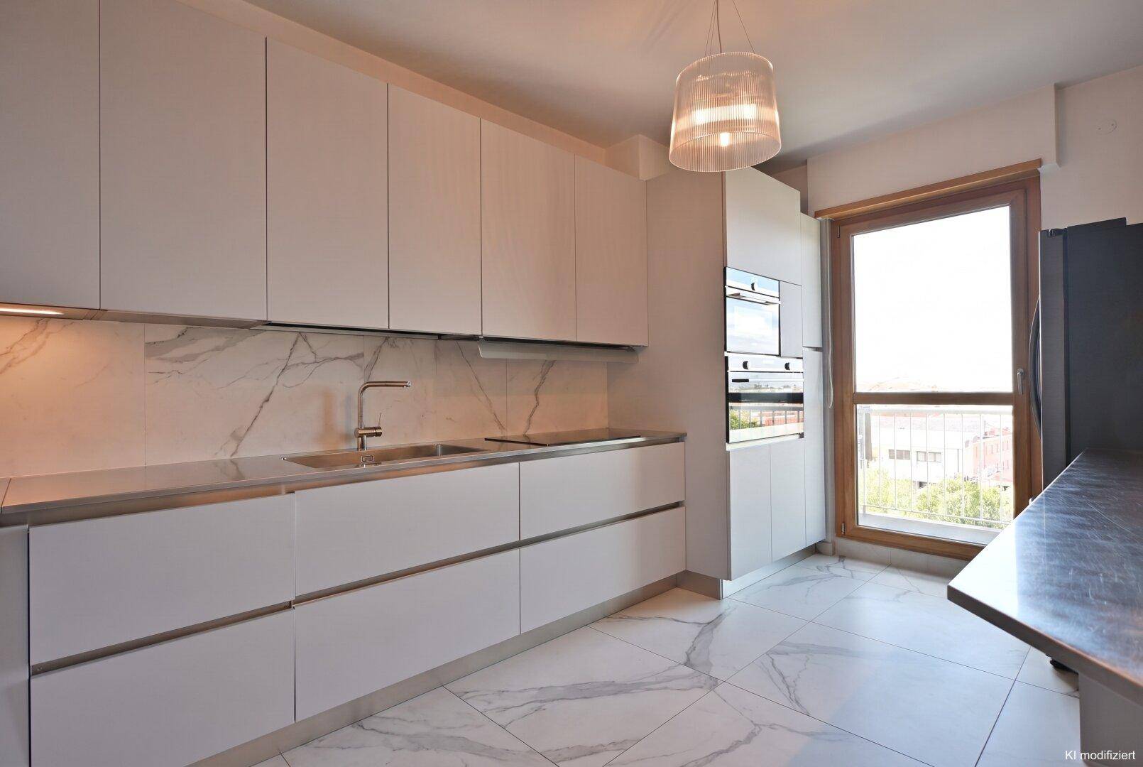 Helle, moderne Küche mit weißen Fronten, integrierten Geräten und großem Fenster.