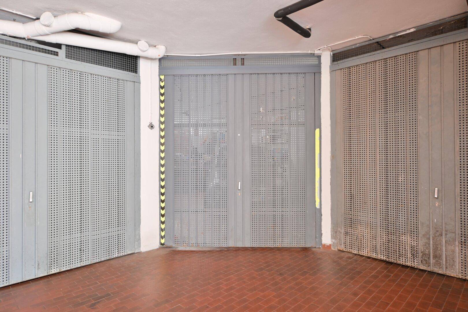 Tiefgarage mit mehreren Garagentoren und Ziegelboden.