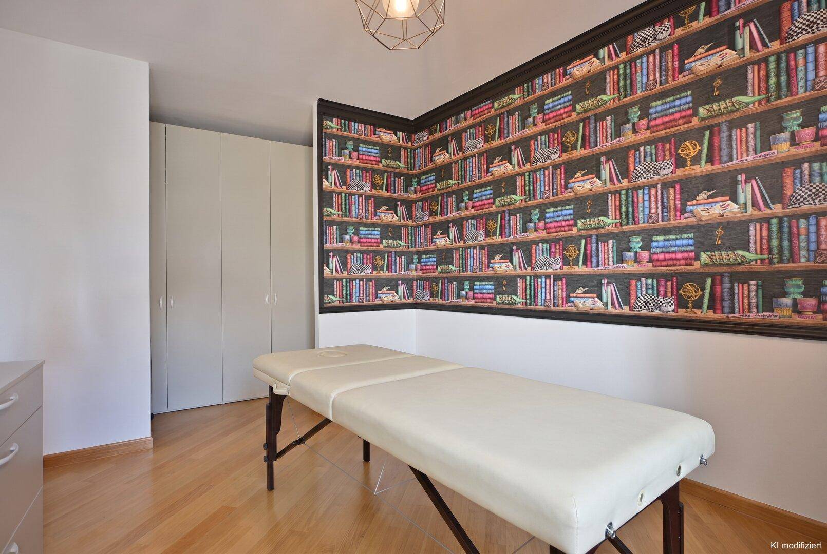 Heller Raum mit Holzboden, Bücherregal-Tapete und einer Liege.