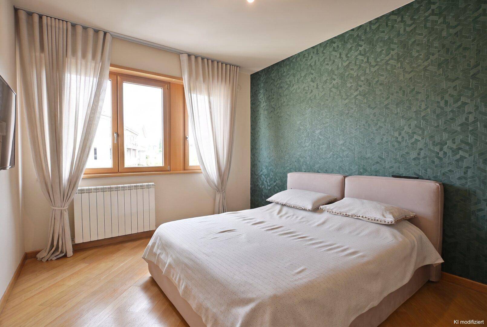 Helles Schlafzimmer mit Doppelbett, Holzboden und einer grünen Akzentwand.
