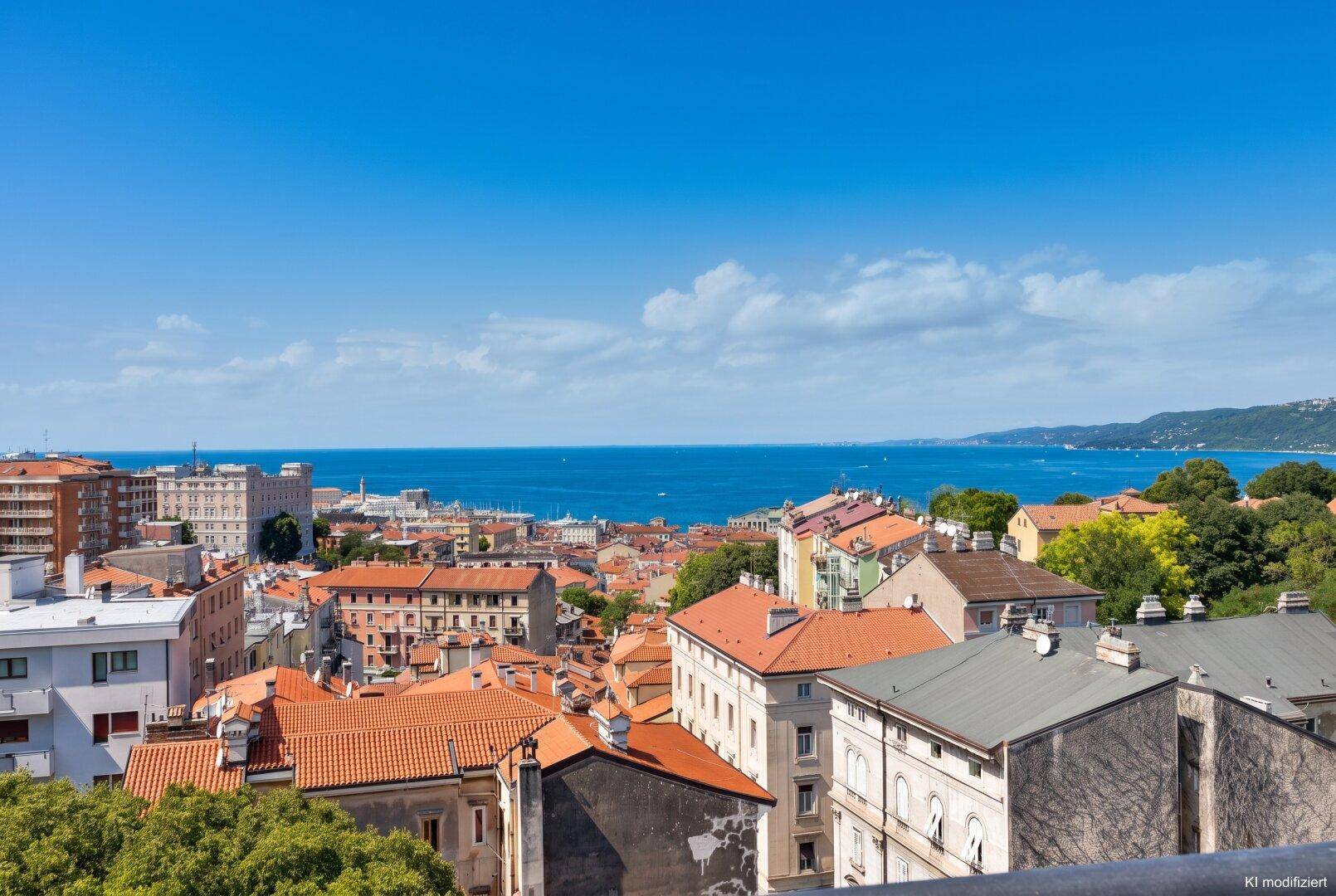 Malerischer Ausblick auf die Stadt mit ihren charakteristischen Dächern und dem tiefblauen Meer am Horizont.