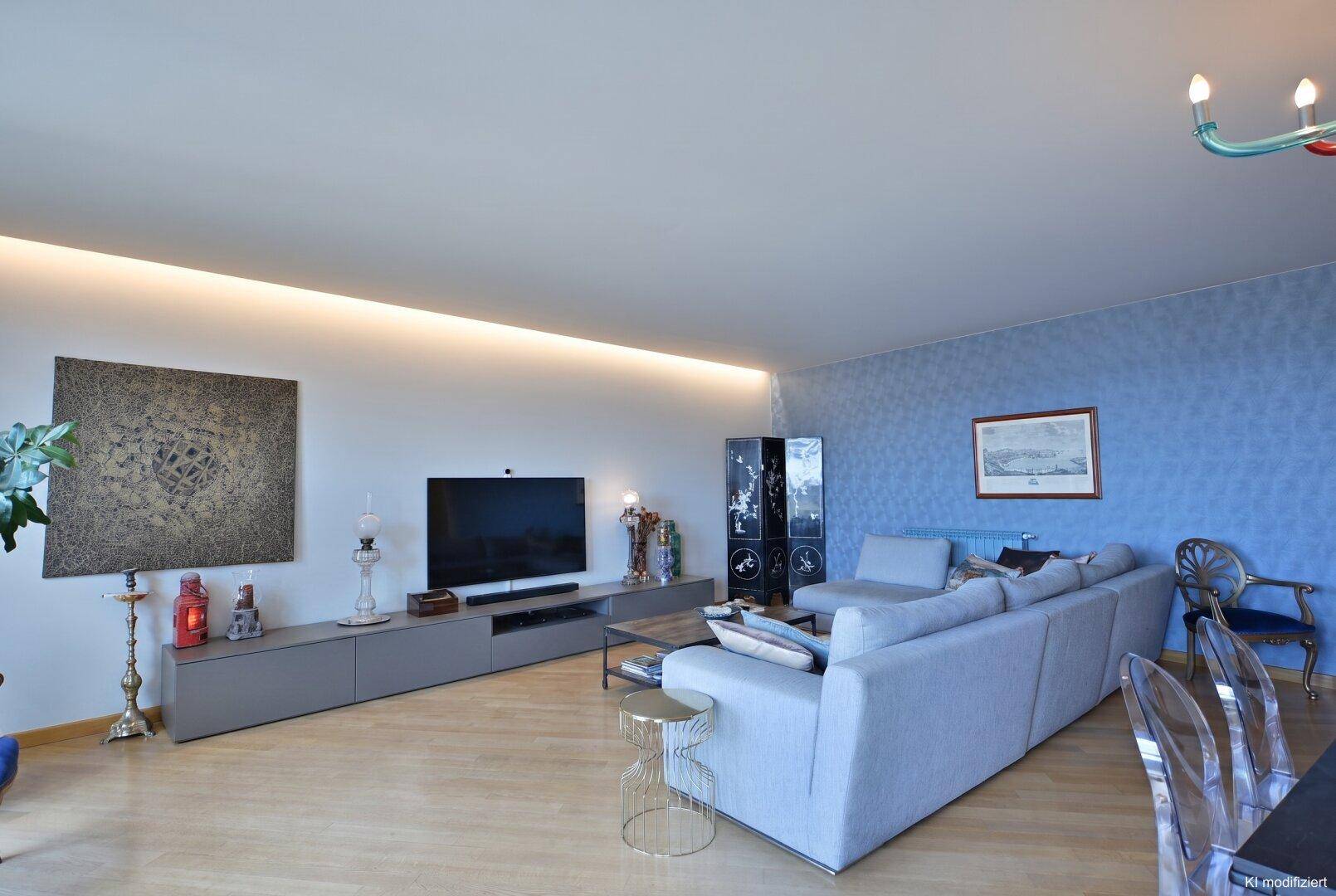 Helles Wohnzimmer mit großem Sofa, Fernseher und einer stilvollen blauen Wandgestaltung.
