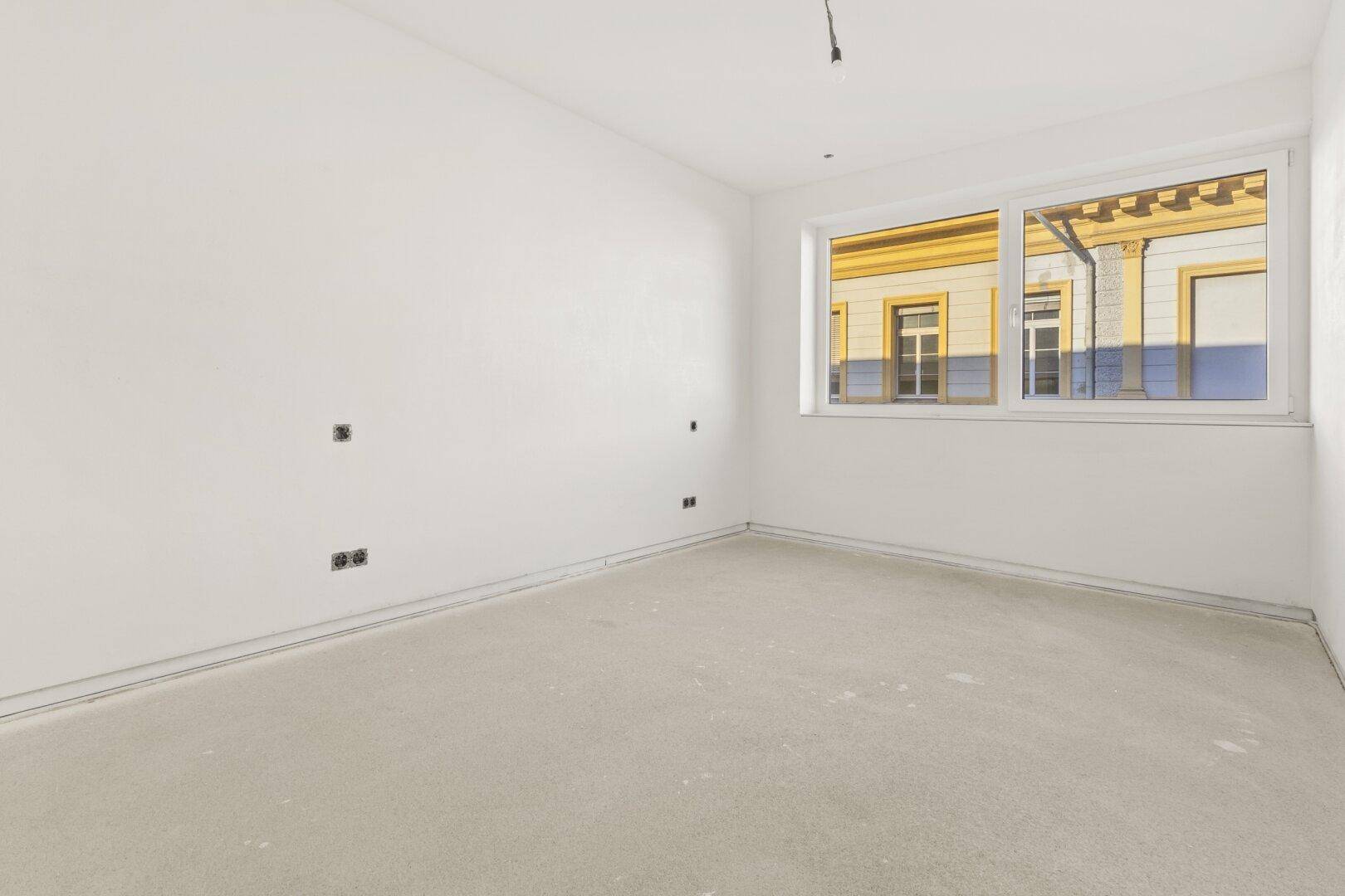 Helles Zimmer mit großem Fenster und Blick auf die gegenüberliegenden Gebäude, bietet viel Tageslicht.