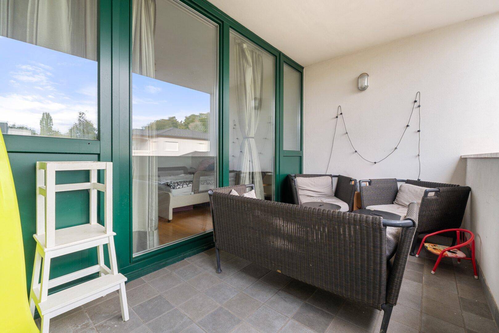 Gemütlicher Balkon mit Rattanmöbeln und Blick ins Grüne, ideal zum Entspannen.