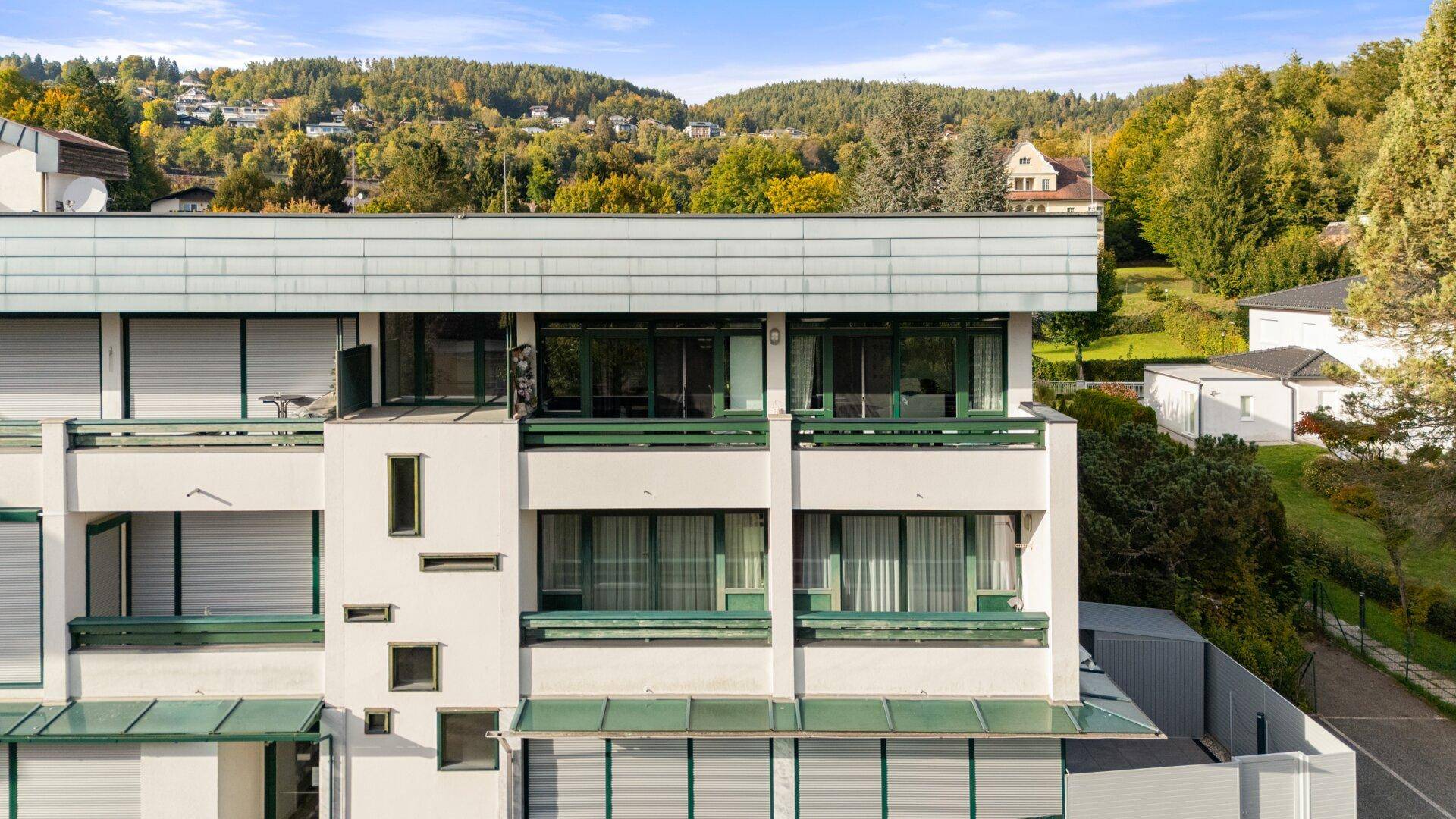 Detailansicht der Gebäudefassade mit Balkonen und Blick auf die bewaldeten Hügel.