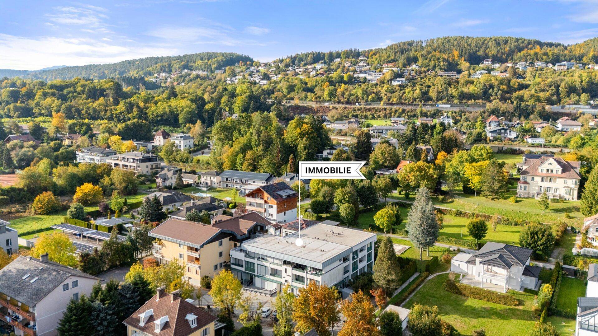 Weitläufige Luftaufnahme der Immobilie eingebettet in eine grüne Hügellandschaft.