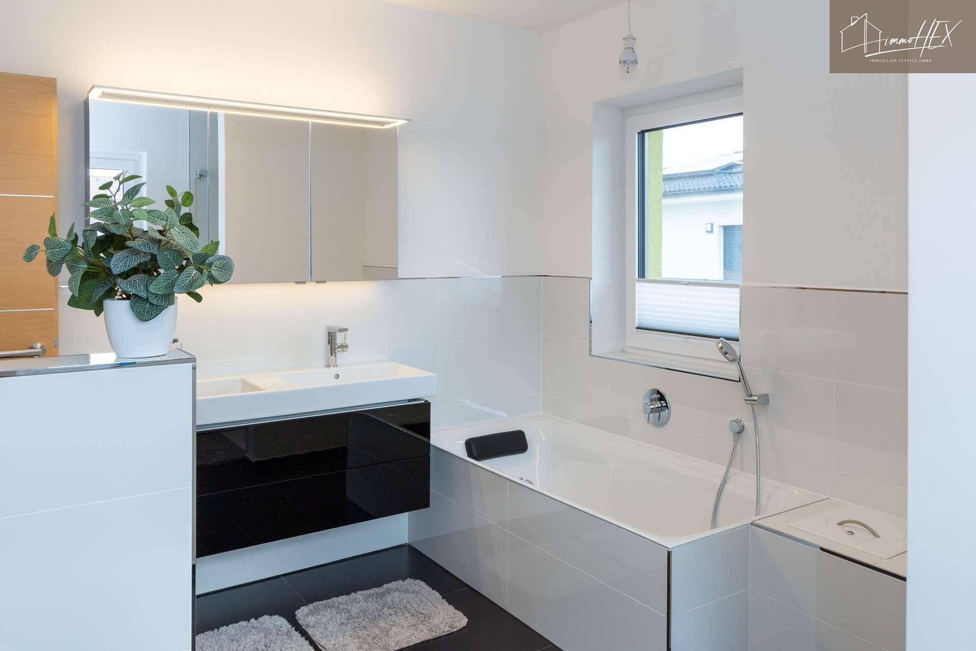 Stilvolles Badezimmer mit Doppelwaschbecken, Spiegelschrank und Badewanne, alles in modernem Design gehalten.
