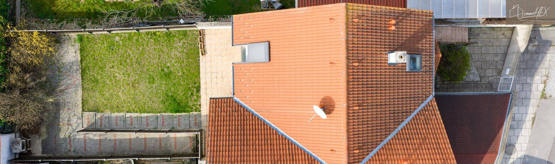 Luftaufnahme des Hauses mit Ziegeldach, Garten und umliegenden Grundstücken.
