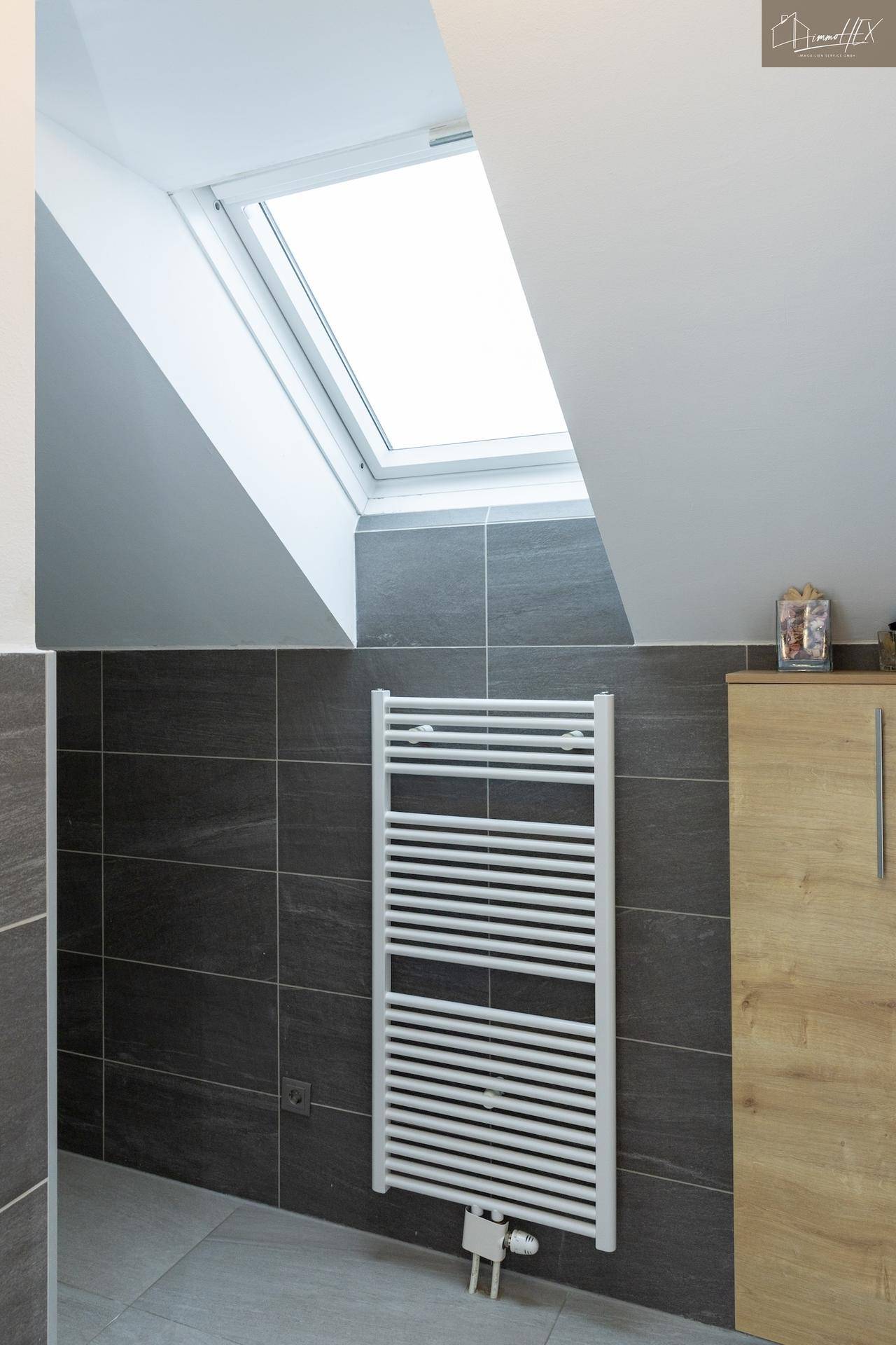 Modernes Badezimmer mit Heizkörper für Handtücher und Dachfenster.
