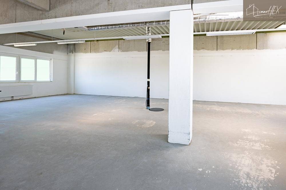 Leerer Bürobereich mit einer tragenden Säule, Betonboden und viel Potenzial für die Einrichtung.