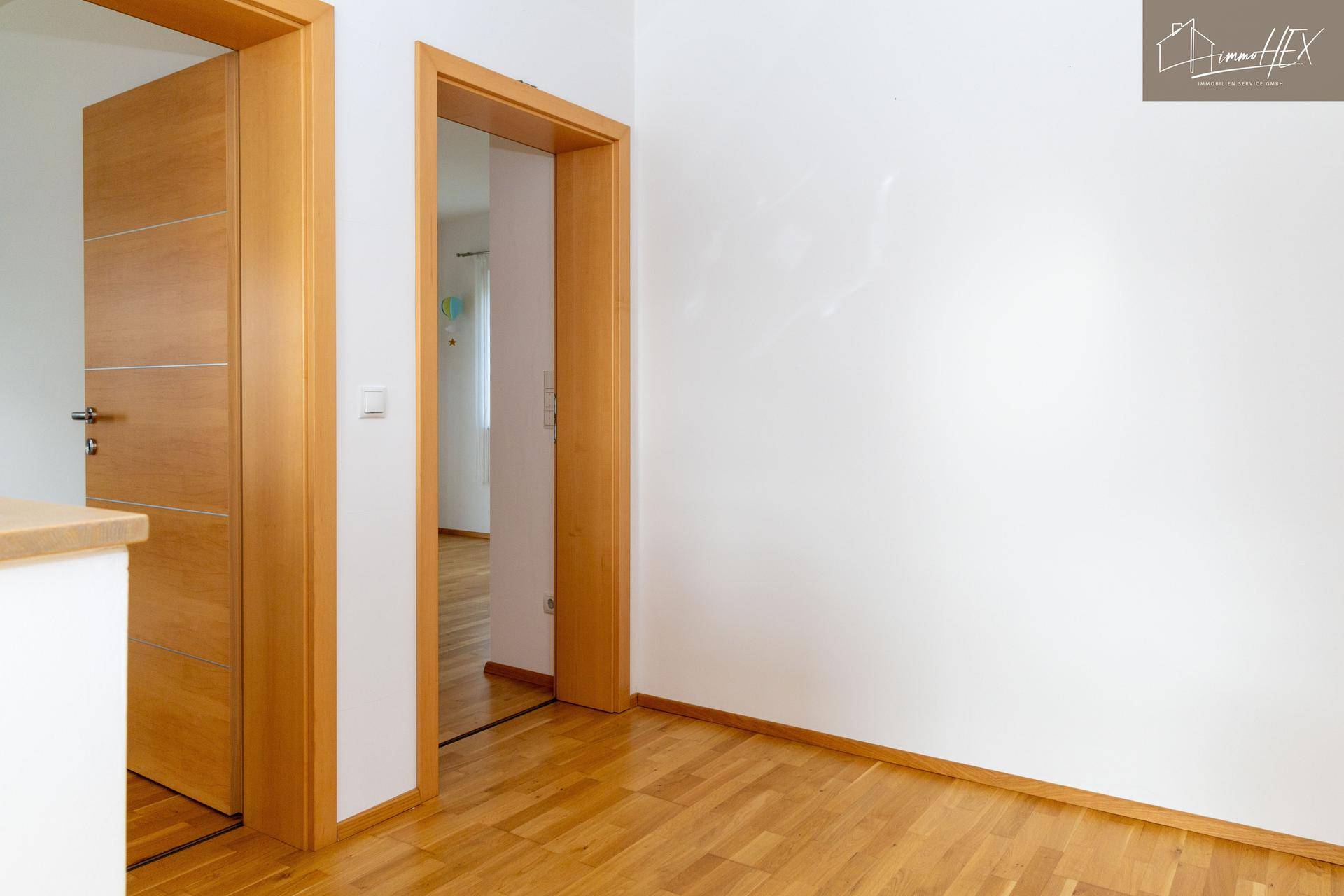 Moderner Flur mit Holztüren und hellem Parkettboden, schlicht und funktional.