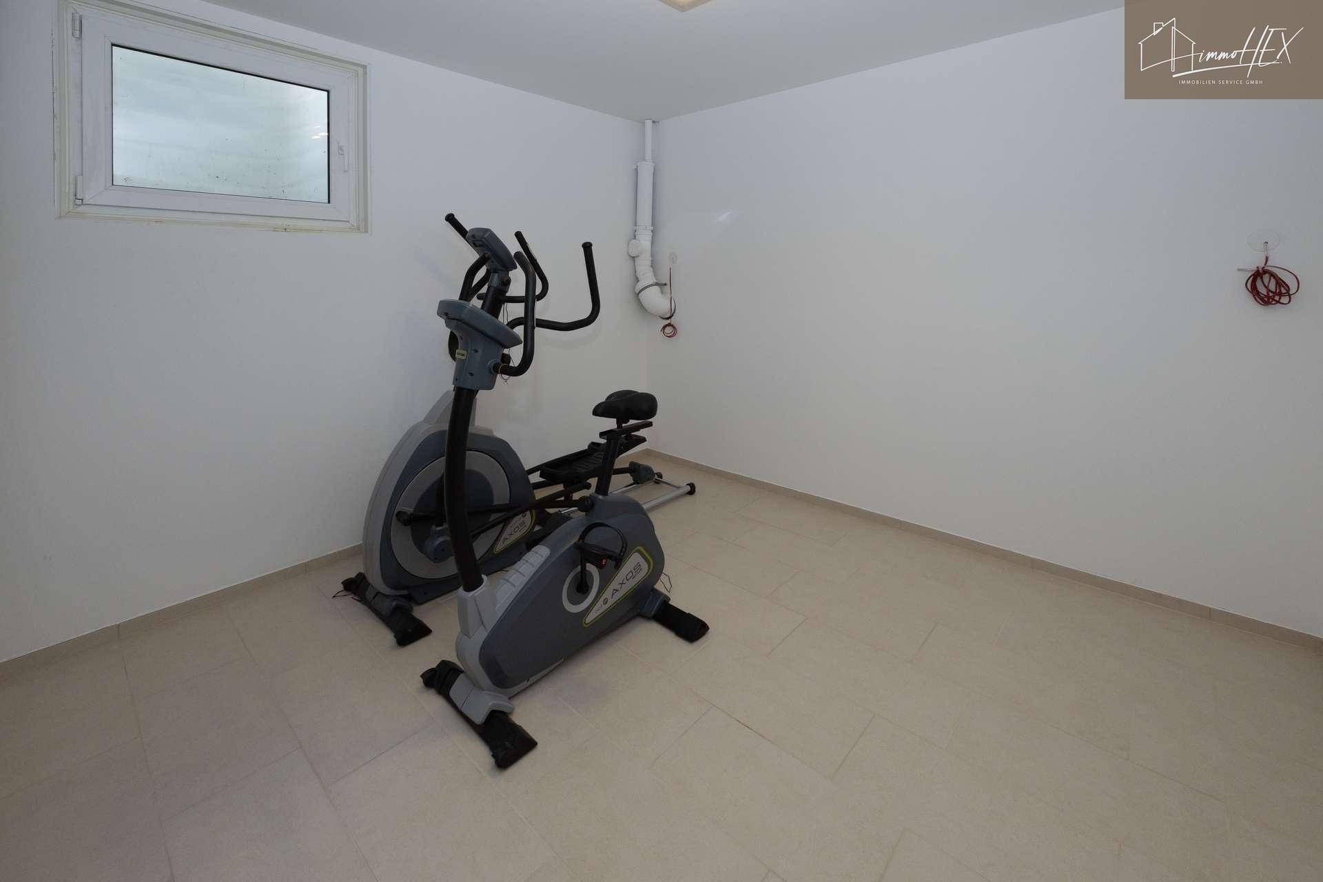 Geräumiger Fitnessraum mit einem Trainingsgerät und Fenster, bietet Platz für Bewegung.