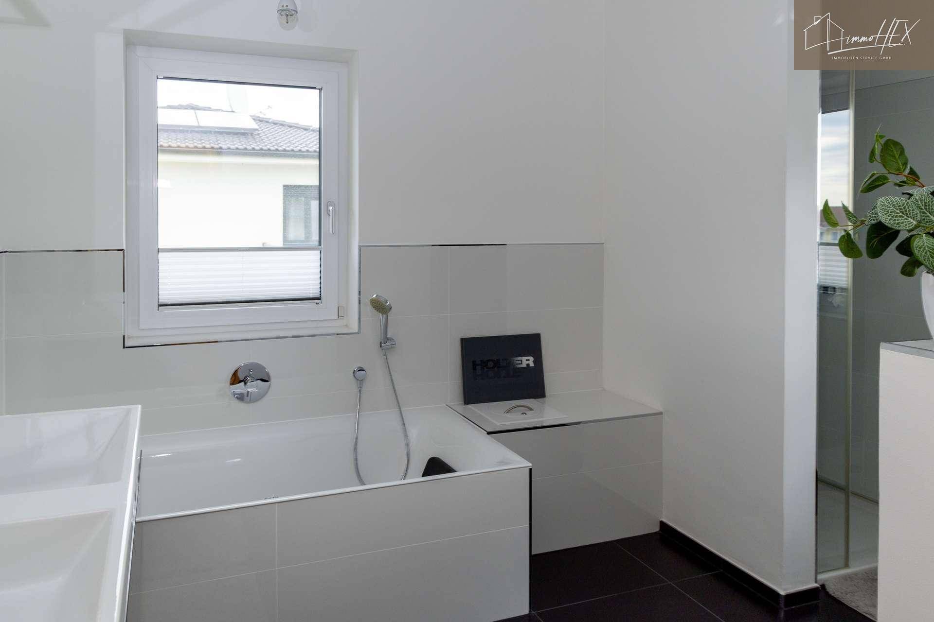 Modernes Badezimmer mit Badewanne, Duschkopf und Fenster.