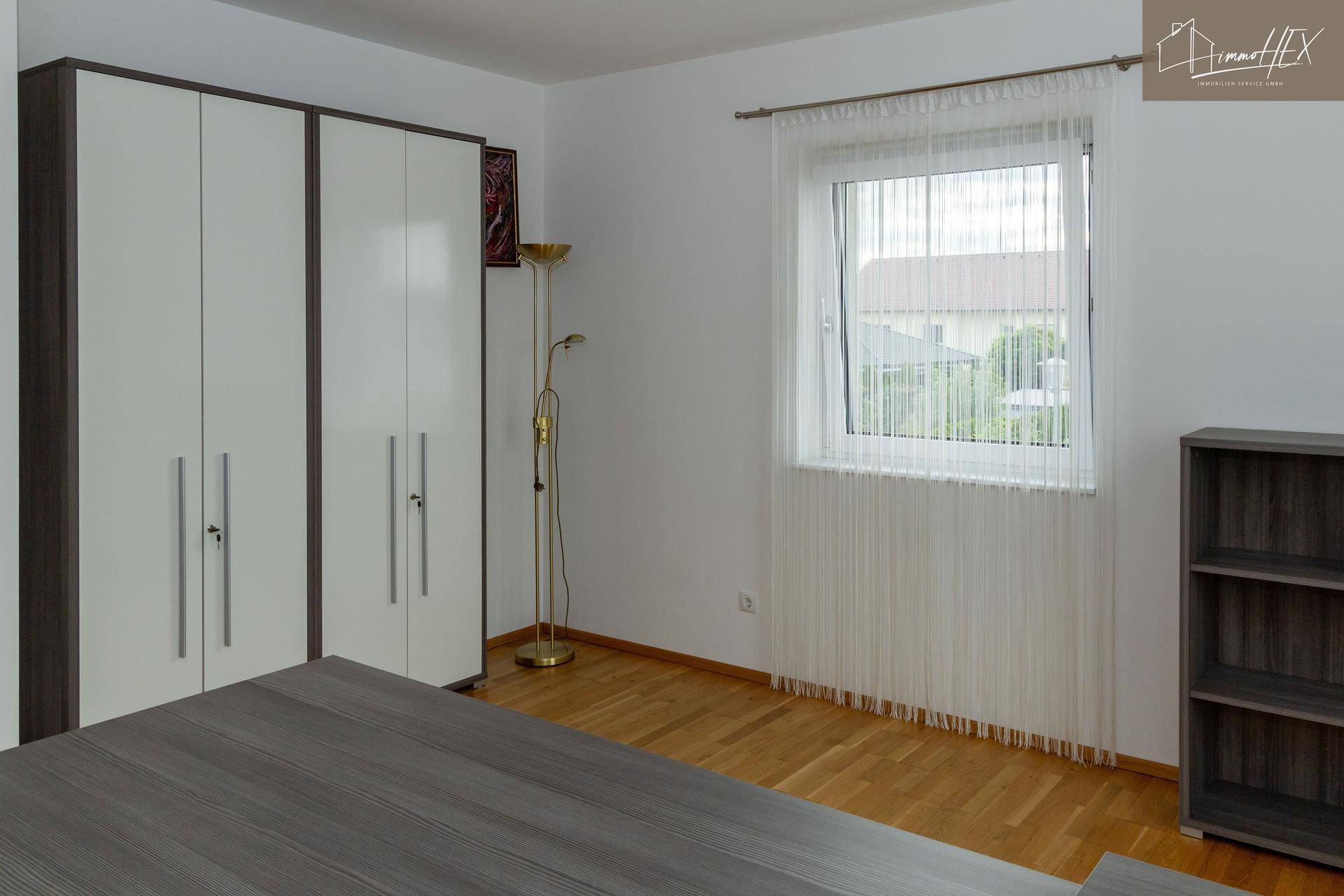 Büro mit Holzboden, Fenster und weißem Kleiderschrank.