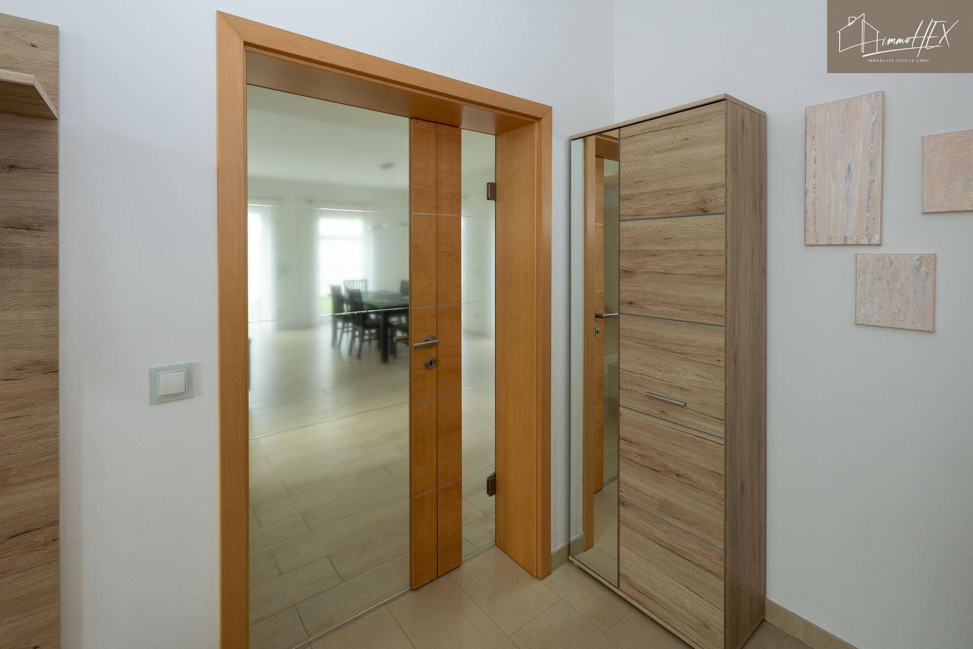 Flur mit Holztüren und einem Spiegelschrank, der den Blick in den Essbereich freigibt.