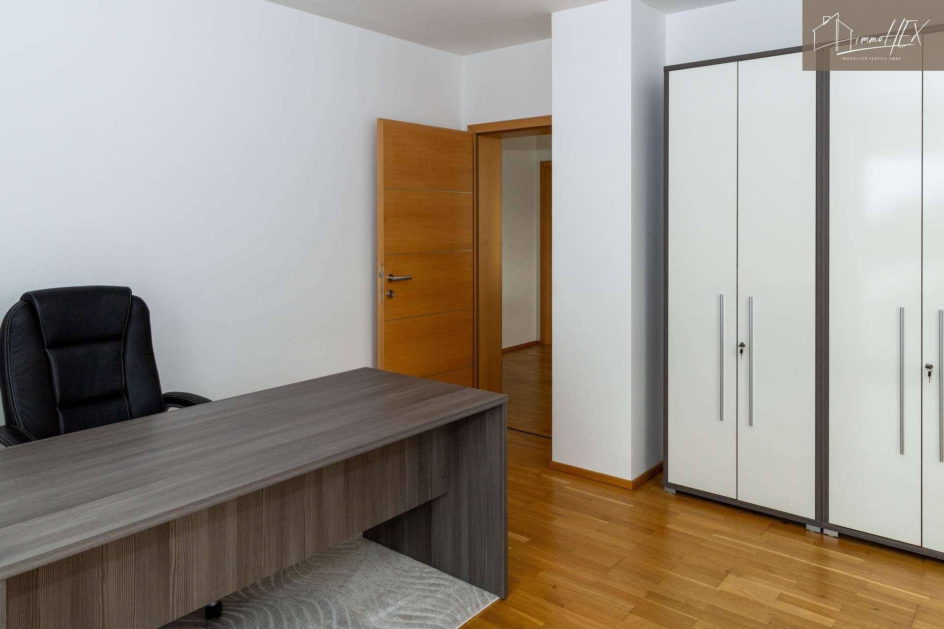 Geräumiges Arbeitszimmer mit Holzboden, Schreibtisch und praktischen weißen Kleiderschränken für Stauraum.