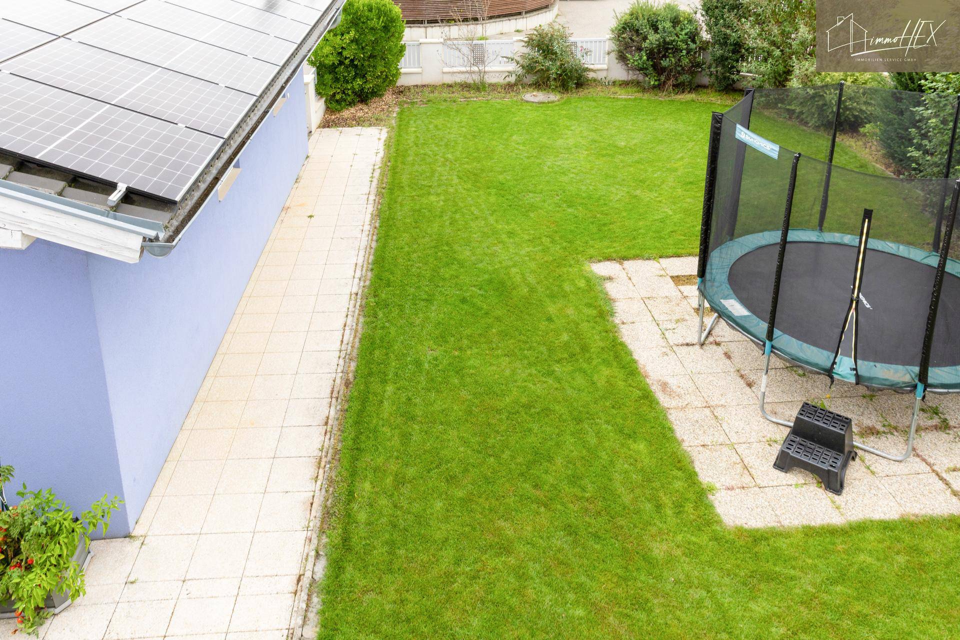 Gepflegter Gartenbereich mit Rasenfläche und Trampolin, ideal für Familien.