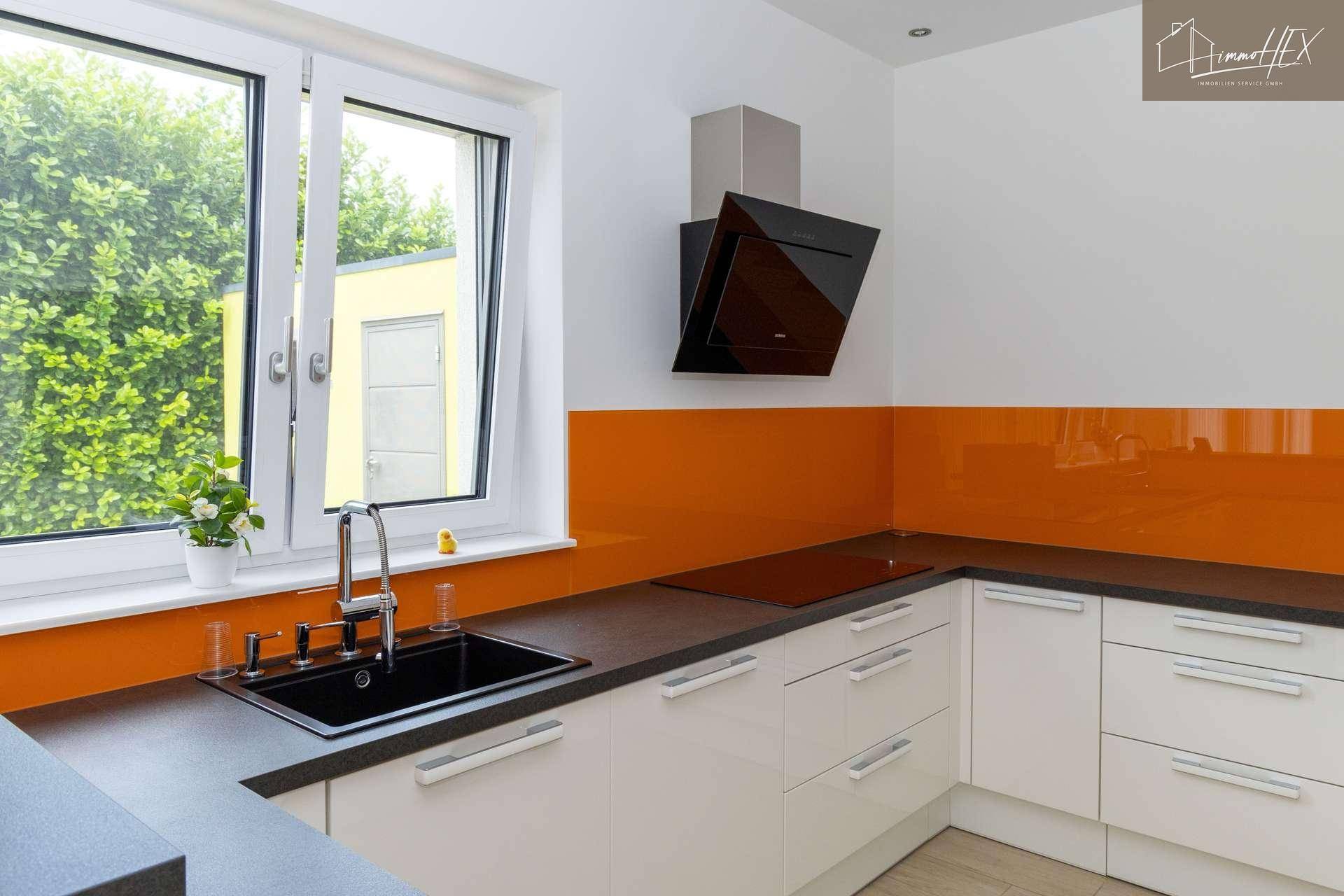 Funktionale Küche mit Spüle, Induktionskochfeld, Dunstabzugshaube und Fenster.