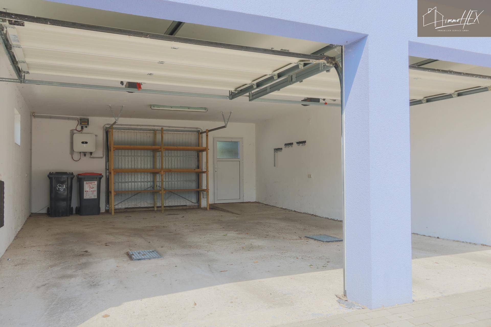 Innenansicht einer Garagenhälfte mit Betonboden, kleinem Fenster und Lagerregal.