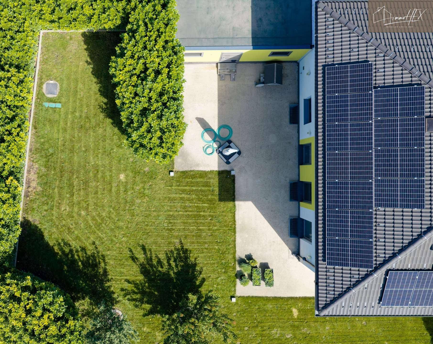 Luftaufnahme des Gartens mit Rasenfläche, Terrasse und angrenzendem Hausbereich.