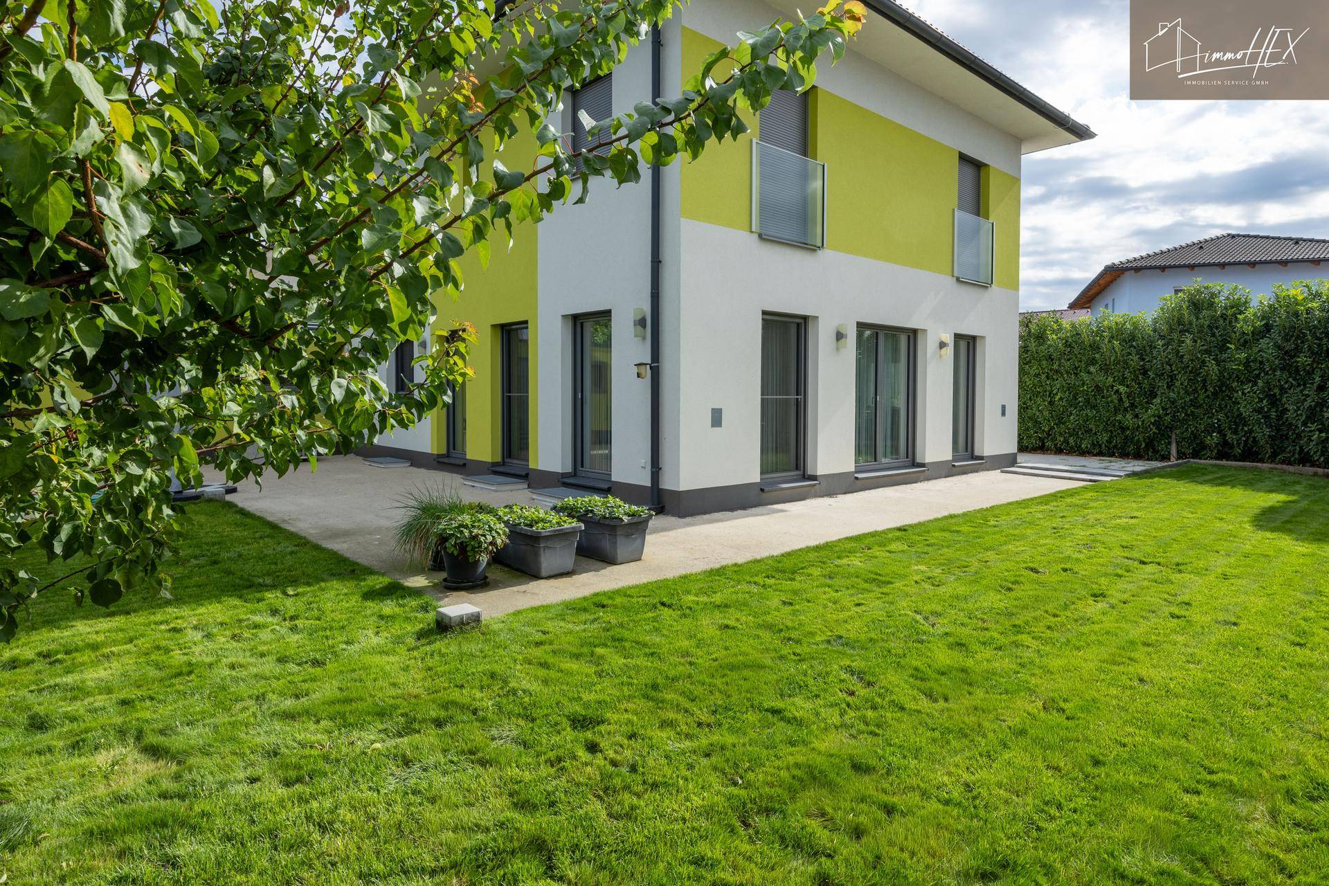Ansicht des Hauses mit Terrasse und großem Garten, umgeben von viel Grün.
