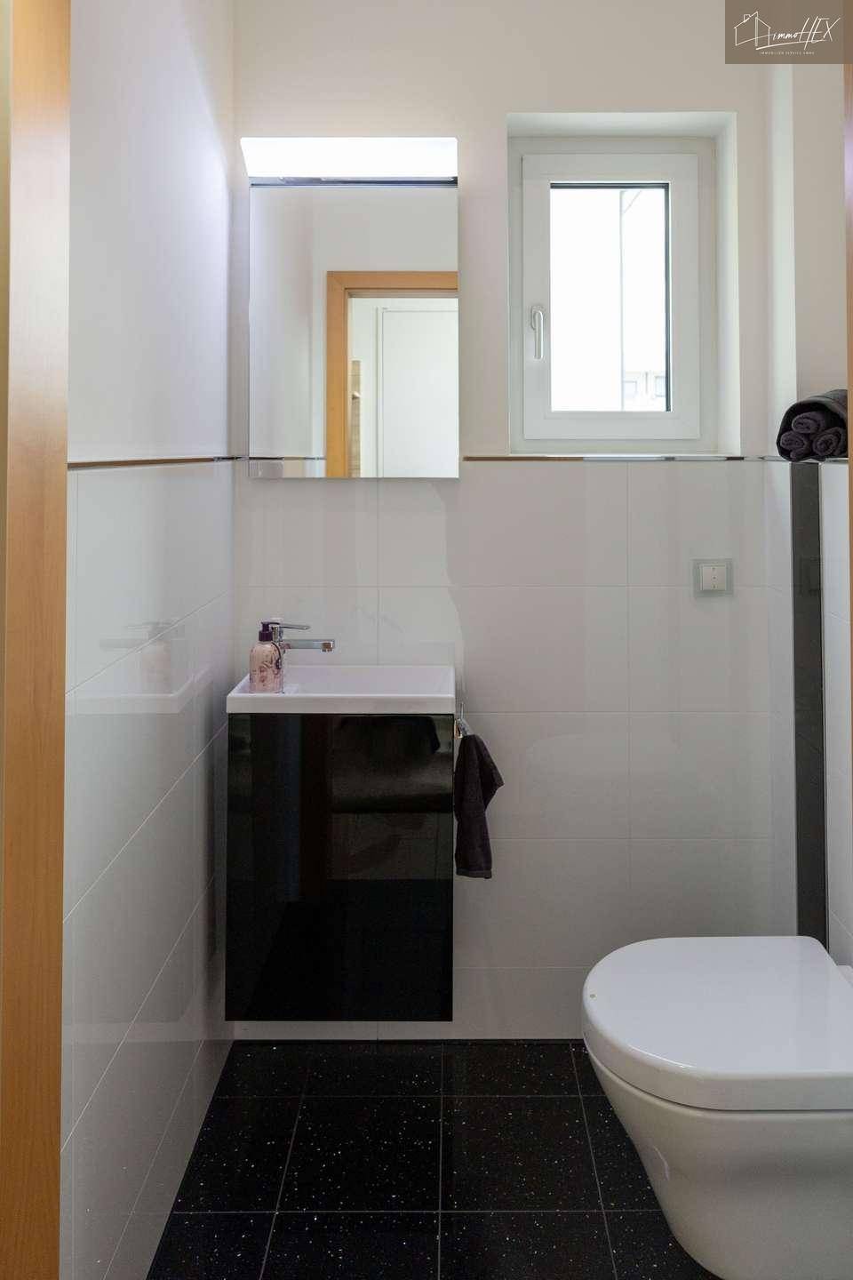 Modernes Gäste-WC mit schwarzem Boden und weißem Waschbeckenunterschrank.