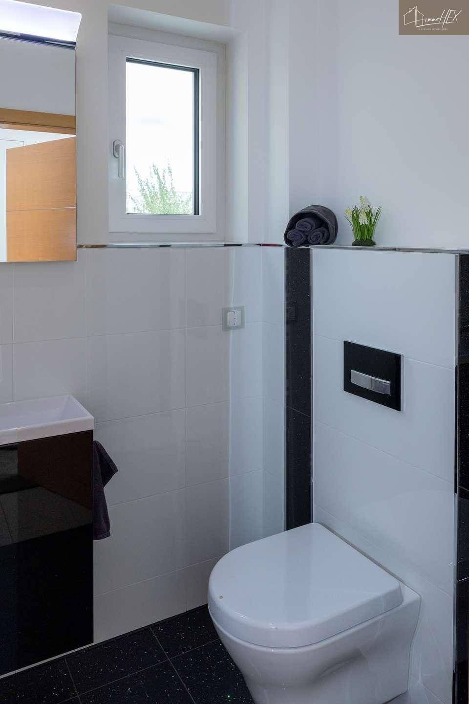 Modernes Gäste-WC mit schwarzem Fliesenboden und weißer Wandgestaltung.