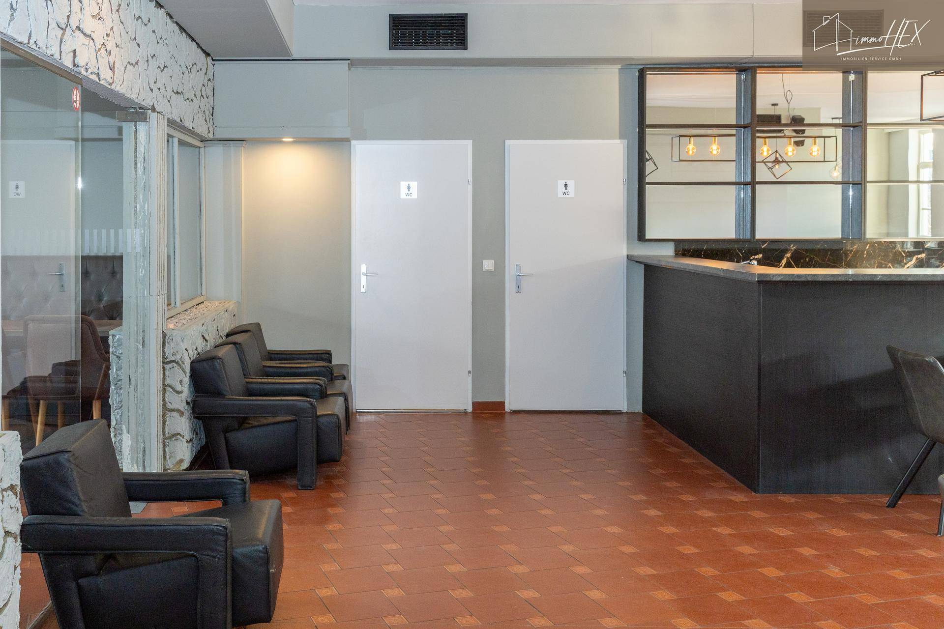 Wartebereich mit bequemen Ledersesseln und Zugang zu den Toiletten.