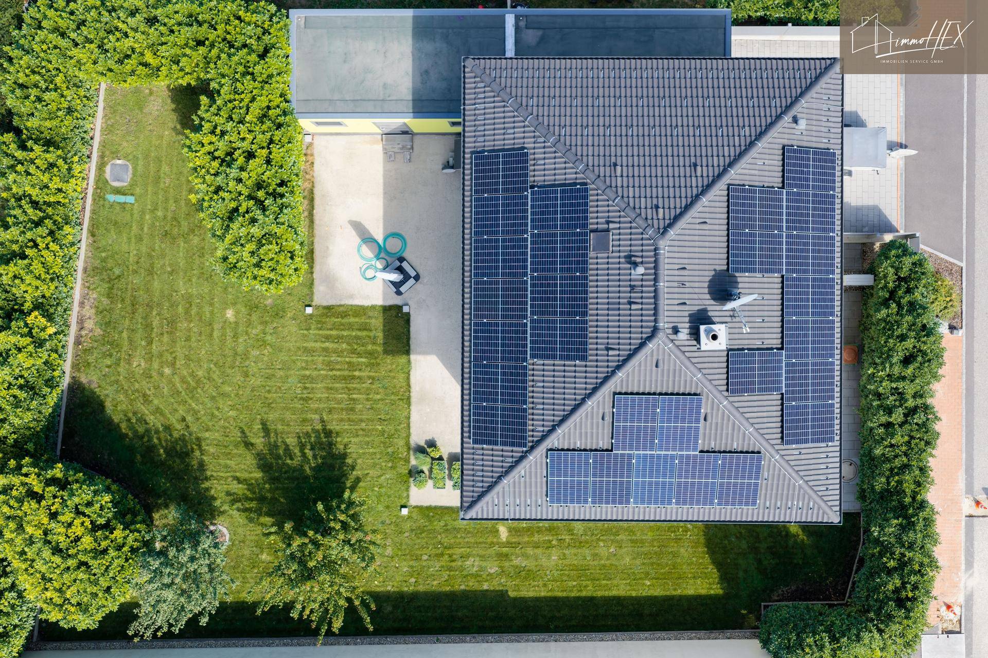 Vogelperspektive des Hauses mit Solarmodulen auf dem Dach und weitläufigem Gartenbereich.